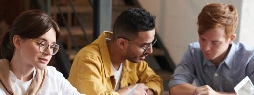 Three colleagues reviewing work together at a desk